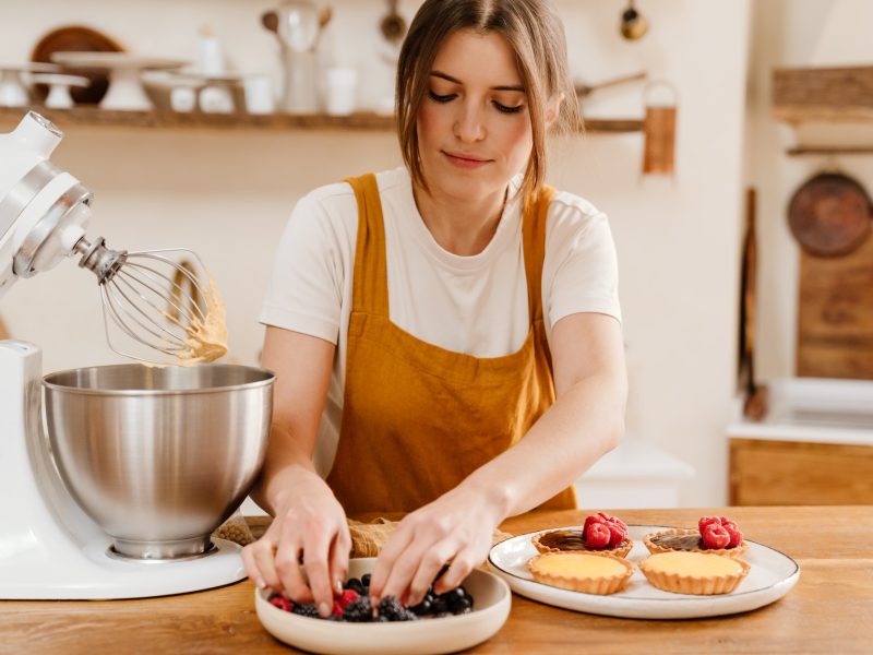 Beautiful concentrated pastry chef woman making tarts with berries